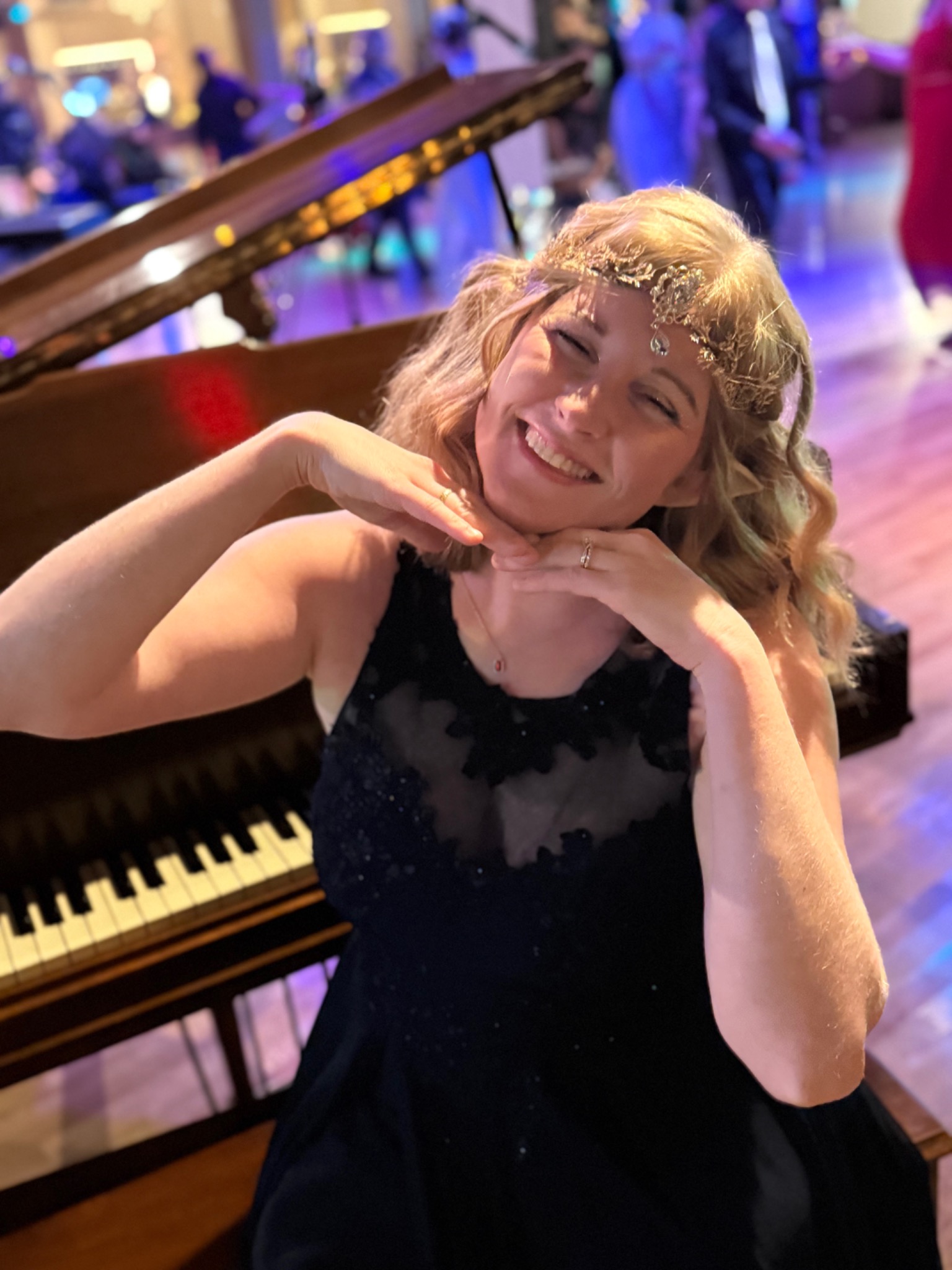 Maggie Moon smiling beside a grand piano in an elven-style headpiece